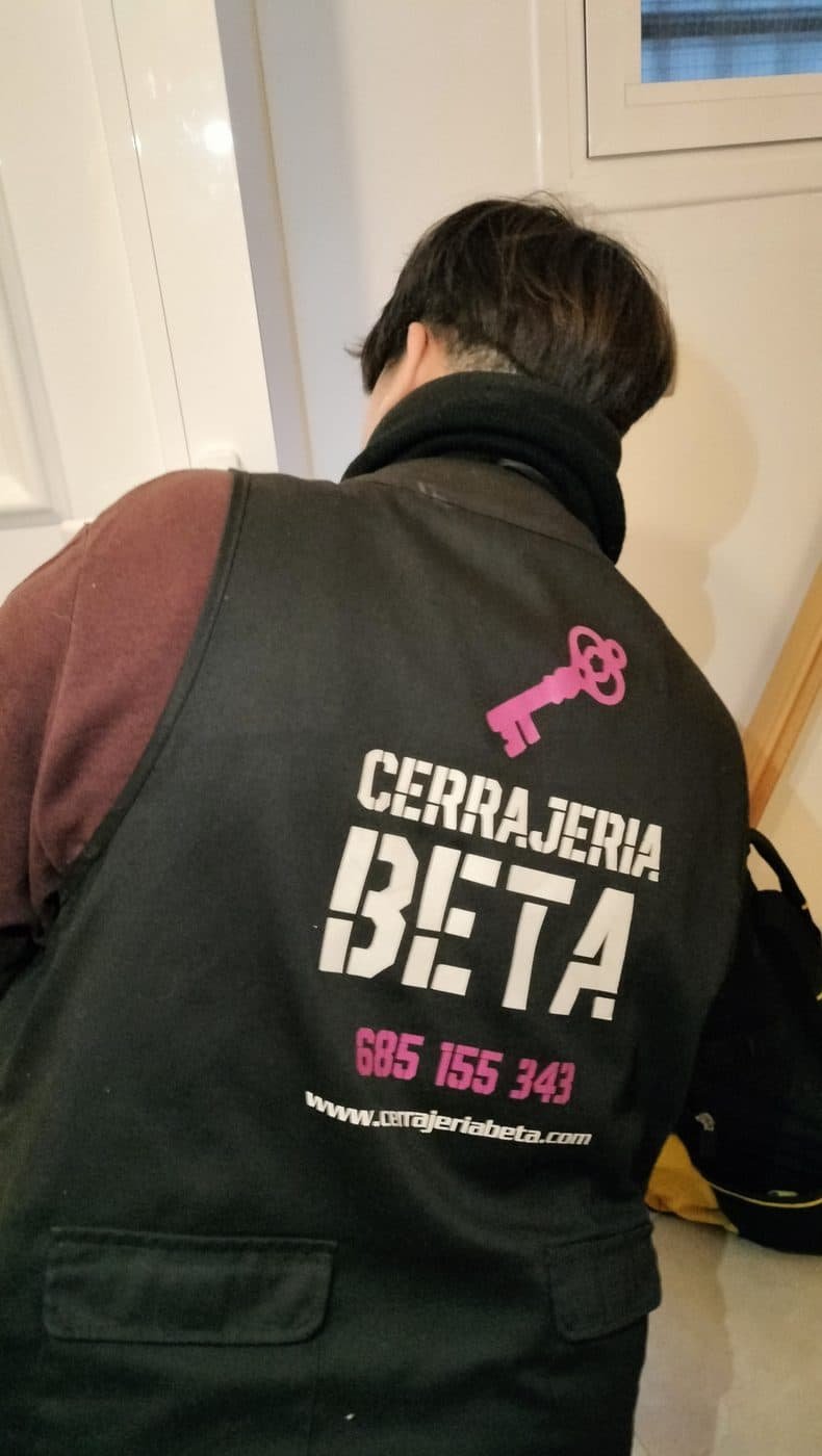 Profesional de Cerrajería BETA, de espaldas, con el chaleco de la empresa durante un servicio a domicilio