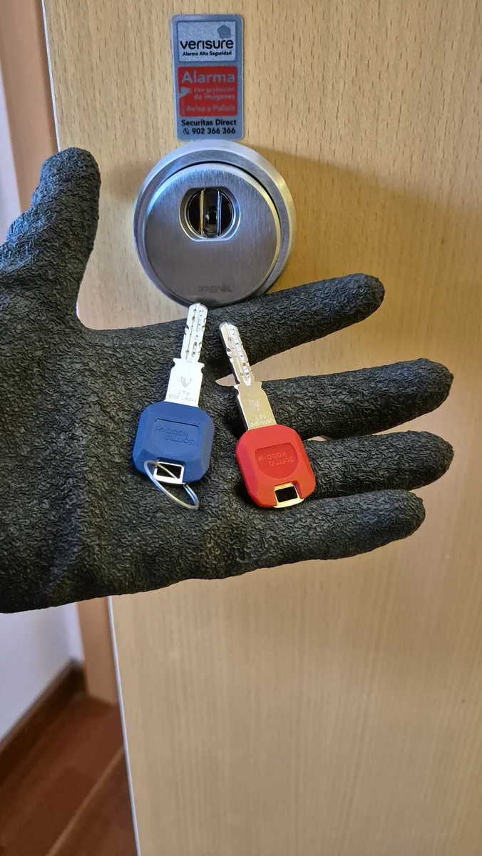 Escudo de seguridad instalado en una puerta y dos llaves sostenidas con guante profesional
